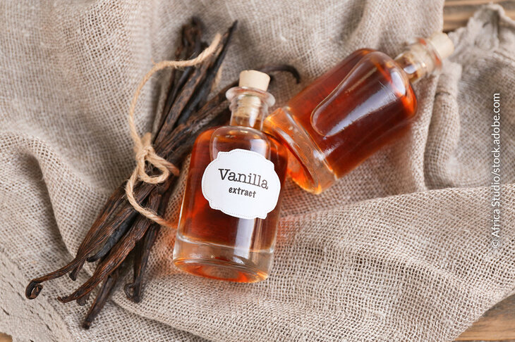 Fläschen mit Vanille-Extrakt aus echter Vanille, dazu Vanilleschoten im Hintergrund