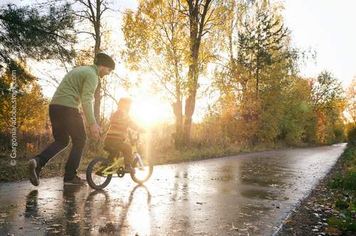 Kind auf Fahrrad mit Elternteil nebenan