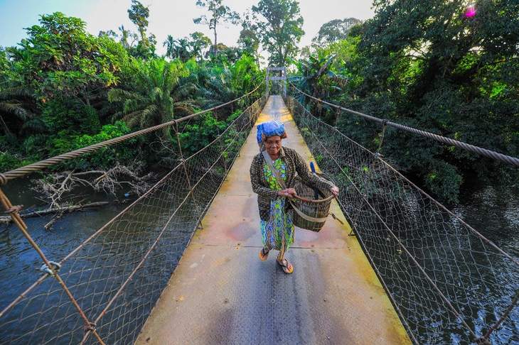 Eine Frau überquert einen Fluss auf einer Hängebrücke